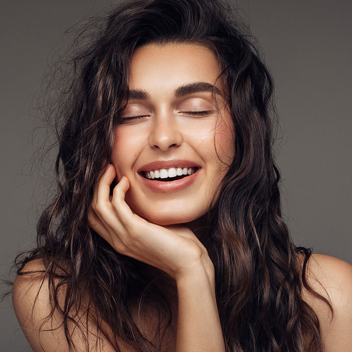 beautiful woman smiling with hand under chin