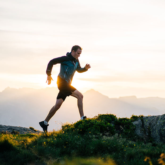 man running on mountain ridge at sunrise