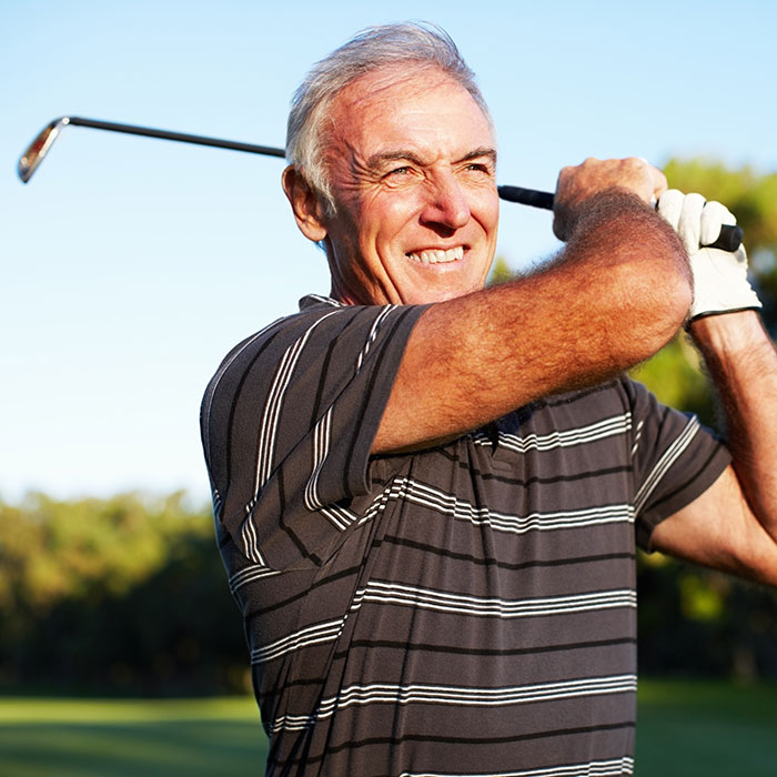 mature man swinging golf club